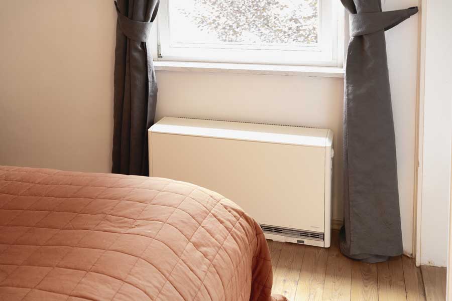 Nachtspeicherheizung ersetzen - Nachtspeicherofen vor Fenster in einem Schlafzimmer.